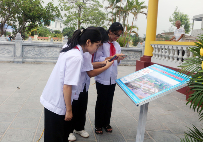 Học sinh quét mã QR để tìm hiểu thân thế, sự nghiệp nhà văn Nam Cao tại khu lưu niệm. Ảnh: Nguyễn Chinh - TTXVN Hà Nam đón nhận Bằng xếp hạng di tích quốc gia - di tích lịch sử Mộ và Khu lưu niệm Nam Cao ảnh 3