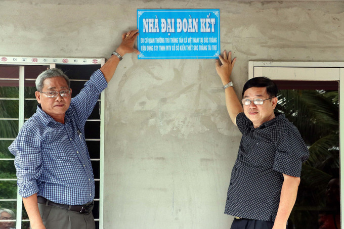 Gắn biển bàn giao Nhà đại đoàn kết cho hộ bà Trần Thị Mỹ Vân. Ảnh: Trung Kiên - TTXVN Thông tấn xã Việt Nam chung tay hỗ trợ nạn nhân bị ảnh hưởng chất độc da cam tại Sóc Trăng ảnh 3
