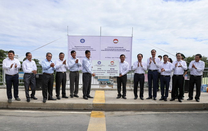 Đoàn Campuchia trao bảng tượng trưng tặng 5 căn nhà Đại đoàn kết cho đại diện lãnh đạo tỉnh An Giang. Ảnh: Thanh Sang - TTXVN. Bàn giao nhà Đại đoàn kết và tặng quà cho người dân vùng biên giới Việt Nam - Campuchia ảnh 2
