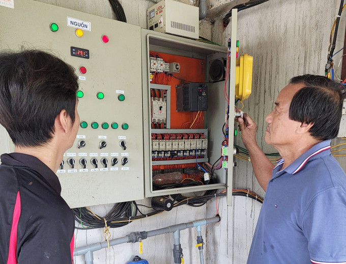 Ông Lê Văn Quyết hướng dẫn nhân viên sử dụng công nghệ cao chăm sóc đàn gà tại trang trại. Ảnh: Lê Xuân - TTXVN Ông Lê Văn Quyết đi đầu trong chăn nuôi công nghệ cao ảnh 1