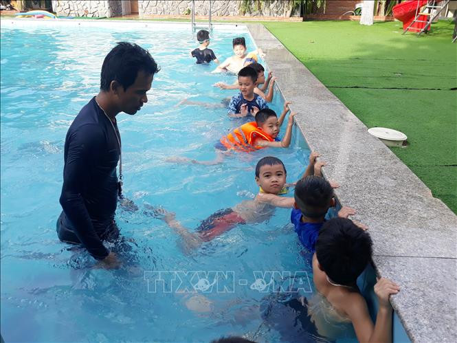 Giáo viên Trường Liên cấp Hoa Sen (thành phố Phan Rang – Tháp Chàm, tỉnh Ninh Thuận) hướng dẫn học sinh tiểu học kỹ năng bơi lội. Ảnh: Nguyễn Thành – TTXVN Cần thiết đưa môn học kỹ năng bơi lội vào trường học ảnh 1
