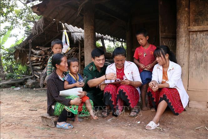 Cán bộ Đồn Biên phòng Mường Lạn hướng dẫn đồng bào vùng biên học chữ. Ảnh: Hữu Quyết - TTXVN Điểm tựa giúp đồng bào vùng biên Sơn La ổn định cuộc sống ảnh 3