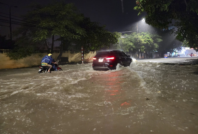 Các phương tiện di chuyển khó khăn trên đoạn đường ngập sâu ở thành phố Điện Biên Phủ. Ảnh: Xuân Tư – TTXVN Mưa lớn kéo dài gây ngập úng cục bộ tại Điện Biên ảnh 1