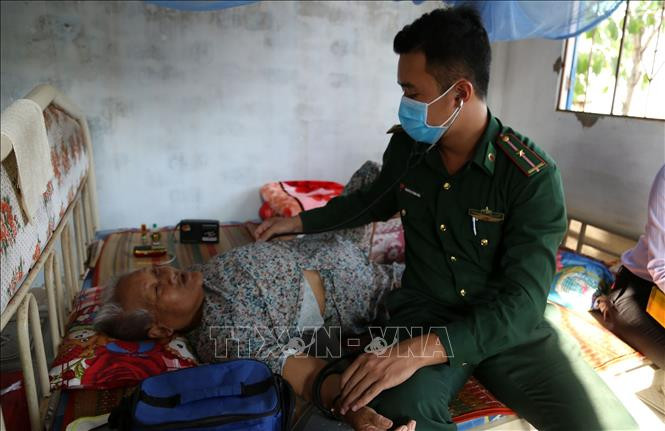 Y sĩ của Trạm xá kết hợp quân dân y đến nhà để khám bệnh cho thân nhân gia đình chính sách. Ảnh: Hữu Chí - TTXVN Hiệu quả từ mô hình quân dân y kết hợp tại Tiền Giang ảnh 3