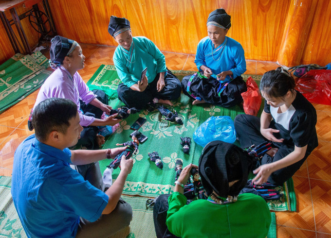 Cán bộ Huyện đoàn Xín Mần cùng đoàn viên thanh niên các thôn, bản thường tập trung làm trang phục dân tộc búp bê vào những lúc nhàn rỗi. Ảnh: Nam Thái - TTXVN Hà Giang: Những người trẻ góp phần gìn giữ bản sắc văn hóa dân tộc ảnh 1