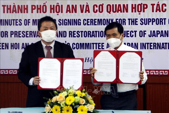 Ông Nguyễn Văn Sơn, Chủ tịch Ủy ban nhân dân thành phố Hội An trao đổi văn bản ký kết hỗ trợ với ông Shimizu Akira, Trưởng Đại diện Văn phòng JICA Việt Nam. Ảnh: Trịnh Bang Nhiệm - TTXVN Chuyên gia Nhật Bản hỗ trợ tu bổ di tích Chùa Cầu ảnh 2