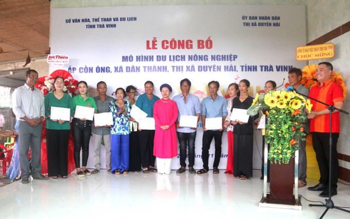Các hộ dân làm du lịch tại Cồn Ông nhận giấy chứng nhận hoàn thành khóa tập huấn làm du lịch cộng đồng. Ảnh: Thanh Hòa- TTXVN Công bố mô hình Du lịch nông nghiệp ấp Cồn Ông ảnh 4