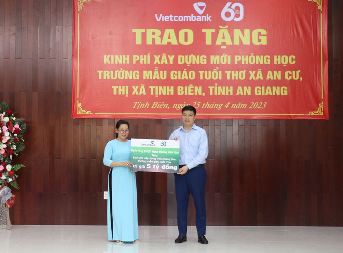 Ông Hồng Quang (phải), Chủ tịch Công đoàn, thành viên Hội đồng quản trị Vietcombank trao bảng tượng trưng 5 tỷ đồng cho Ban giám hiệu trường Mầm non Tuổi Thơ, thuộc xã An Cư, thị xã Tịnh Biên, tỉnh An Giang. Ảnh: Công Mạo-TTXVN Hỗ trợ xây dựng trường mầm non vùng đồng bào dân tộc An Giang ảnh 1