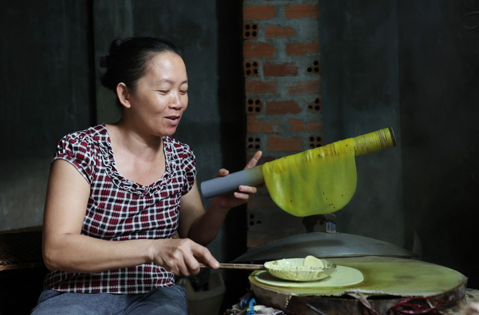 Chị Trần Thị Hiền có hơn 20 năm làm bánh tráng bằng thủ công. Ảnh: Tuấn Anh – TTXVN Làng nghề bánh tráng Hòa Nhơn "chạy" đơn hàng Tết ảnh 1