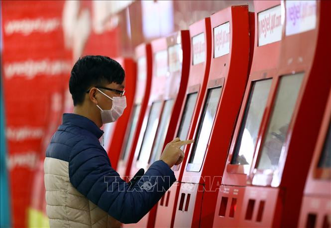 Hành khách làm thủ tục lên máy bay tại quầy check in trực tuyến của Vietjet. Ảnh: Huy Hùng - TTXVN Hành khách đi máy bay vẫn phải kê khai thông tin di chuyển ảnh 1