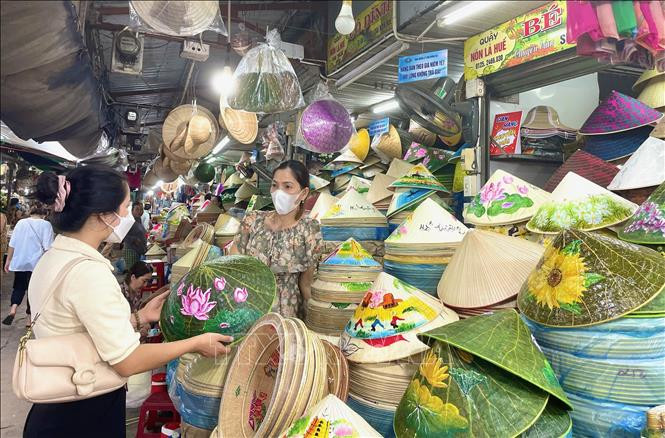 Du khách lựa chọn nón lá làm quà kỉ niệm khi đến chợ Đông Ba. Ảnh: Mai Trang - TTXVN Chợ Đông Ba - điểm đến du lịch truyền thống hấp dẫn ảnh 1