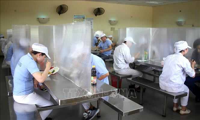 Tại khu vực căng tin trong Khu công nghiệp Hòa Khánh, thành phố Đà Nẵng, các công nhân được bố trí ngồi ăn giãn cách, có vách ngăn. Ảnh: TTXVN Công điện của Thủ tướng Chính phủ về bảo đảm an toàn COVID-19 trong các khu công nghiệp ảnh 2