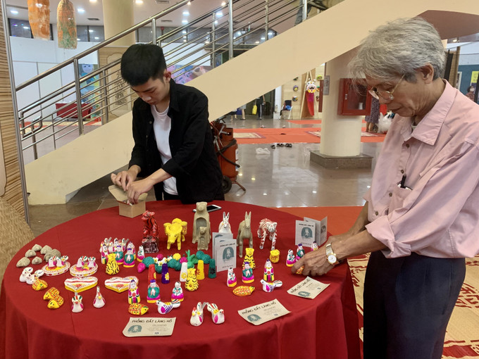 Nghệ nhân Phùng Đình Giáp (bên phải) cùng cháu nội sắp xếp bàn trưng bày phỗng đất của ông tại Trung tâm Triển lãm văn hóa nghệ thuật Việt Nam. Ảnh: Minh Huệ - TTXVN Gìn giữ, lan tỏa giá trị Tết Trung thu cho trẻ em Việt Nam ảnh 1