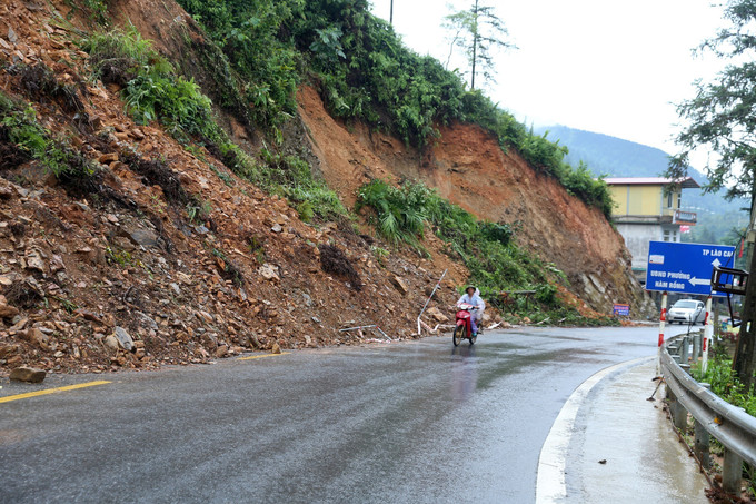 Một điểm sạt lở đất đá xuống lòng đường gây nguy hiểm cho các phương tiện tham gia giao thông trên quốc lộ 4D thuộc phường Hàm Rồng, thị xã Sa Pa. Ảnh: Quốc Khánh - TTXVN Mưa lũ gây nhiều thiệt hại tại Lào Cai ảnh 1
