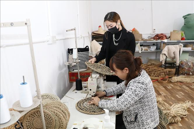 Chị Trần Thùy Nhi (áo đen) kiểm tra sản phẩm của Công ty. Ảnh: Đức Phương - TTXVN Trần Thùy Nhi - Người phụ nữ mang cói Việt ra thế giới ảnh 2