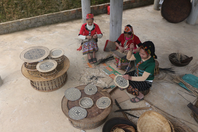 Những phụ nữ bản Diềm (xã Châu Khê, huyện Con Cuông, tỉnh Nghệ An) đan các sản phẩm mây tre có họa tiết từ các sản phẩm thổ cẩm được dệt trên khăn, váy áo của người Thái. Ảnh: Bích Huệ - TTXVN Phát triển sản phẩm lưu niệm, góp phần nâng tầm điểm đến ảnh 2