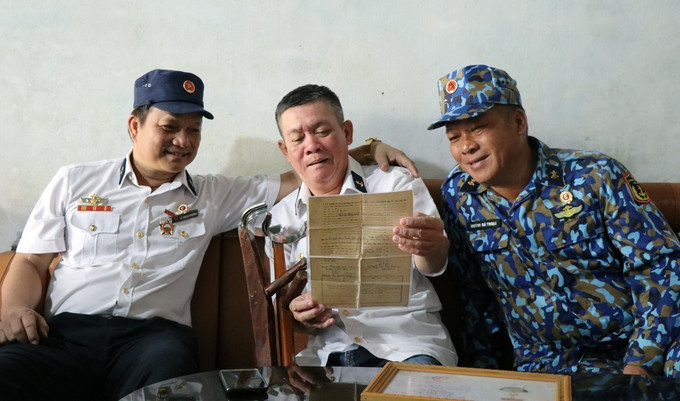 Những đồng đội trong Ban liên lạc Bộ đội Trường Sa Phú Yên xem lại giấy xuất ngũ của thương binh Trần Văn Hùng (thành phố Tuy Hòa). Ảnh: Xuân Triệu - TTXVN Thiêng liêng Gạc Ma những ngày tháng Ba ảnh 3