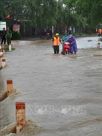 Lực lượng chức năng huyện Ea Súp, Đắk Lắk hỗ trợ, hướng dẫn người dân vượt qua đoạn ngập lụt trên Tỉnh lộ 1. Ảnh: TTXVN Mưa lớn gây ngập lụt cục bộ một số nơi ở Đắk Lắk ảnh 3