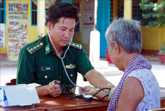 Người “thầy thuốc quân hàm xanh” Lê Văn Quốc khám bệnh cho bà con Khmer nghèo khu vực biên giới biển xã Vĩnh Hải, thị xã Vĩnh Châu, tỉnh Sóc Trăng. Ảnh: Trung Hiếu/Văn Long - TTXVN "Bác sỹ quân hàm xanh" nặng lòng với đồng bào Khmer ở Vĩnh Châu ảnh 1