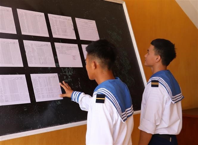 Hai chiến sỹ trẻ lần đầu tiên được đi bầu, theo dõi danh sách cử tri được niêm yết tại UBND xã Song Tử Tây, huyện Trường Sa (Khánh Hòa). Ảnh: TTXVN Huyện đảo Trường Sa hướng tới "Ngày hội non sông" ảnh 4