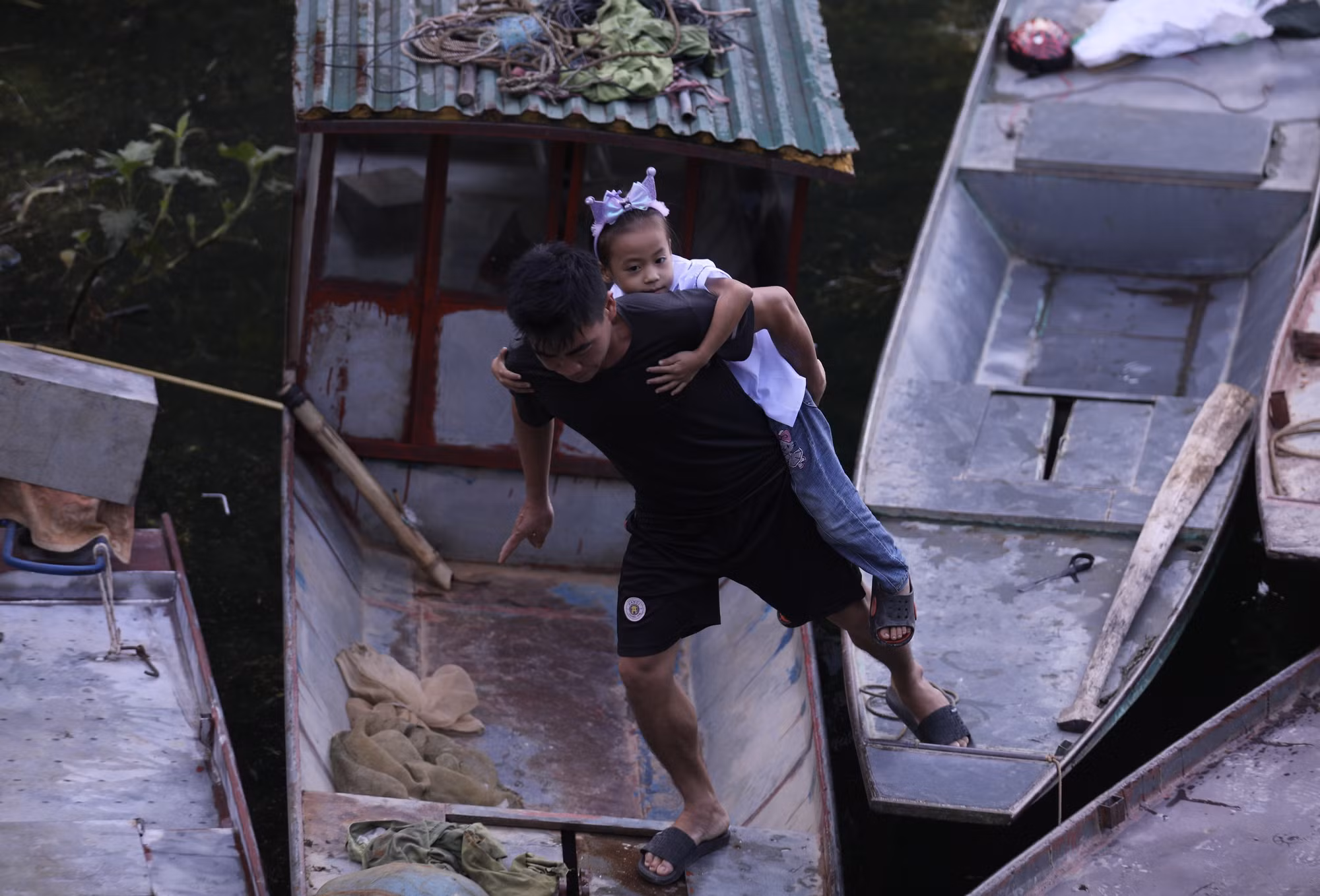 Một phụ huynh cõng con đi qua những con thuyền để kịp dự lễ khai giảng năm học mới tại Trường PTDTBT TH&amp;THCS Vầy Nưa xã Tiền Phong.