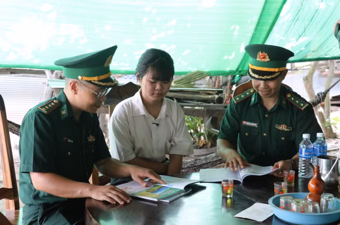 Đại úy Phạm Việt Tiến (đeo kính) thăm hỏi, động viên học sinh được Đồn Biên phòng Cửa khẩu Mỹ Quý Tây nhận nuôi, tiếp thêm động lực để em vượt qua khó khăn, vươn lên trong học tập.