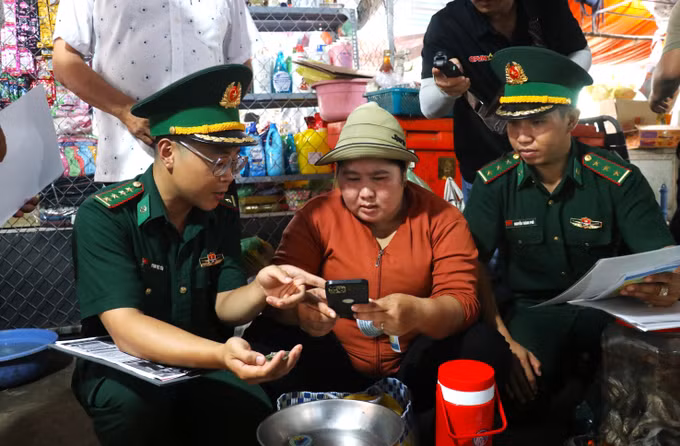 Đại úy Phạm Việt Tiến trò chuyện, tuyên truyền pháp luật cho người dân tại khu vực chợ Tho Mo, đưa những quy định về biên giới, phòng, chống tội phạm đến gần hơn với đời sống.
