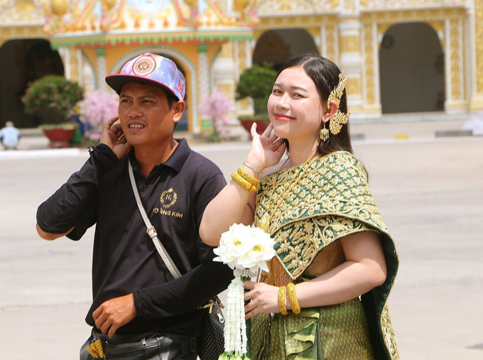 Du khách trải nghiệm mặc trang phục đồng bào Khmer tại chùa Bô Tum Vong Sa Som Rong (Phường 5, thành phố Sóc Trăng). Ảnh: Tuấn Phi-TTXVN potal-thu-hut-du-khach-tu-cac-le-hoi-vung-dan-toc-thieu-so-soc-trang-7985274.jpg