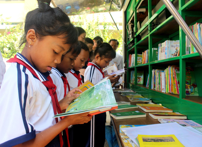 Học sinh thích thú đọc sách tại xe Thư viện lưu động đa phương tiện. Ảnh: Hồng Hiếu- TTXVN potal-binh-thuan-dua-van-hoa-doc-den-cac-xa-kho-khan-vung-dong-bao-dan-toc-thieu-so-7994602.jpg