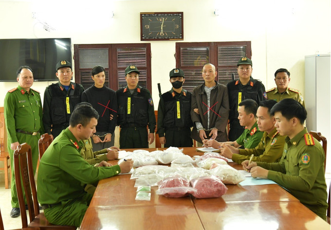 Hai đối tượng Đinh Hồng Thuấn (áo dài xám) và Phạm Lê Tuấn Anh (áo khoác đen) cùng tang vật vụ án. Ảnh: nld.com.vn matuyquangbinh.jpg