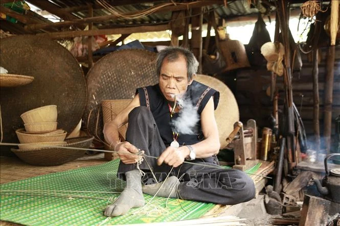 Nghệ nhân Đinh Bi (làng Kgiang, xã Kông Lòng Không, huyện Kbang, tỉnh Gia Lai) dù đã ở tuổi 65 nhưng đôi tay vẫn lanh lợi, đôi mắt sáng trau chuốt từng đường nan. Ảnh: Quang Thái- TTXVN