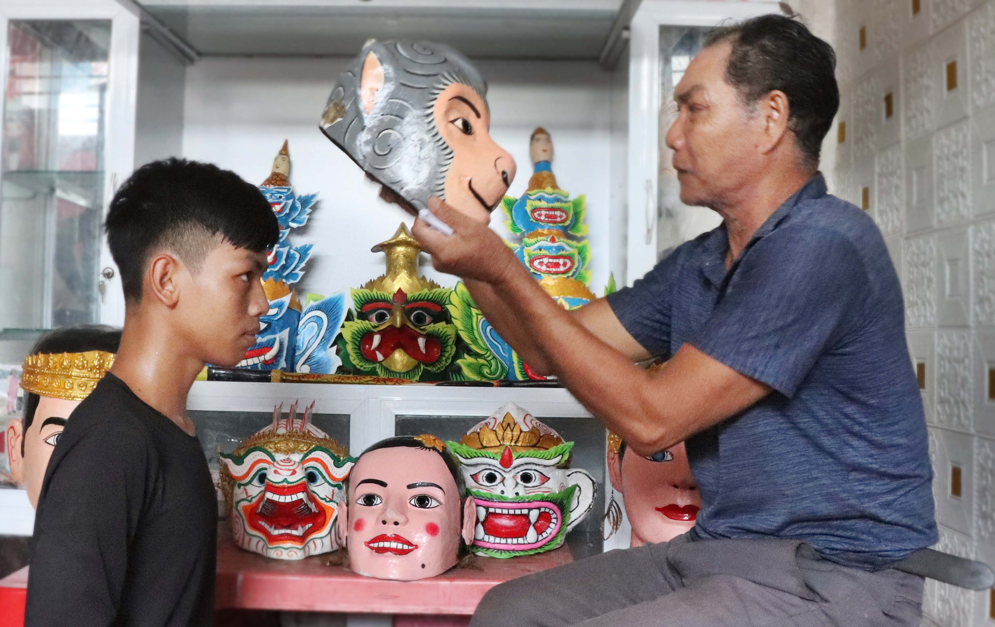Nghệ nhân Thạch Tung mang mão khỉ Hanuman cho thành viên trong đội đóng vai nhân vật. b1-chhaydam.jpg
