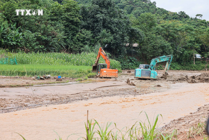 Máy xúc, máy đào được huy động để tìm kiếm tại những vị trí khả năng có nạn nhân. Ảnh: Hoàng Hiếu - TTXVN vna_potal_lang_nu_hoang_tan_sau_lu_du_7600425.jpg