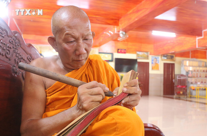 Hòa thượng Chau Sơn Hy, Sư cả chùa Sà Lôn ở xã Lương Phi, huyện Tri Tôn (An Giang), trình diễn kỹ thuật viết kinh bằng chữ Pali trên lá buông. Ảnh: Công Mạo-TTXVN vna_potal_kinh_la_buong_“bau_vat”_cua_dong_bao_khmer_an_giang_7715244.jpg