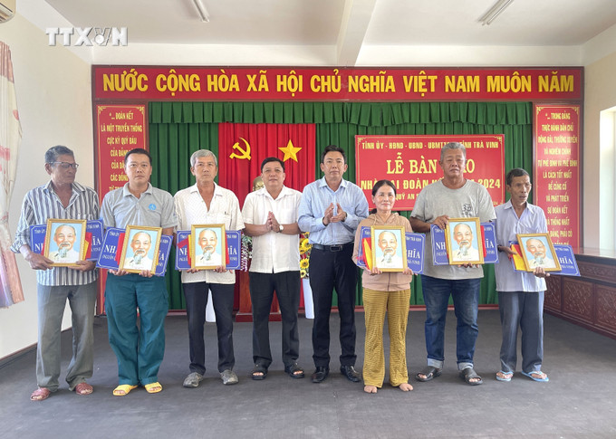 Các hộ dân nhận bảng tượng trưng bàn giao nhà. Ảnh: Thanh Hòa- TTXVN vna_potal_tra_vinh_ban_giao_tren_nha_cho_ho_ngheo_can_ngheo_ho_kho_khan_ve_nha_o_7641539.jpg