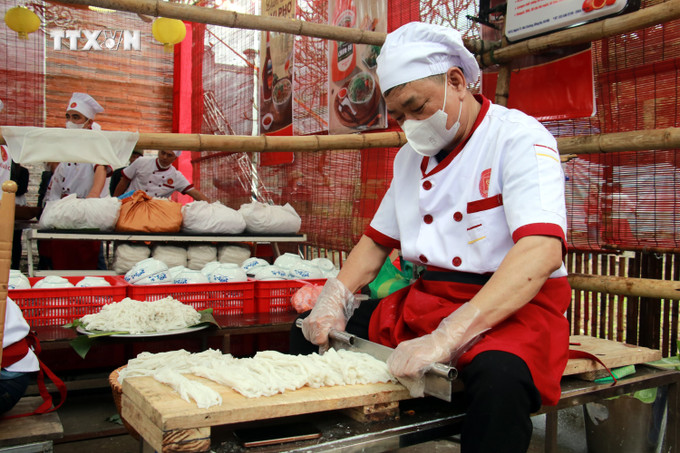 Trình diễn công đoạn thái bánh phở bằng tay. Ảnh: Nguyễn Lành - TTXVN vna_potal_festival_pho_nam_2024_ton_vinh_am_thuc_truyen_thong_nam_dinh_7272739.jpg