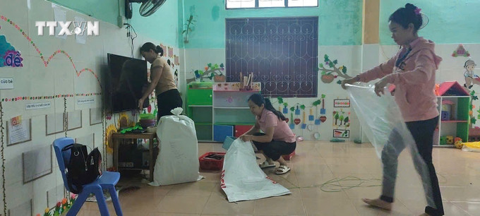 Các giáo viên thu dọn đồ dùng dạy học ứng phó bão số 4. Ảnh: TTXVN phát vna_potal_quang_tri_trien_khai_cac_giai_phap_ung_pho_voi__mua_lon_sat_lo_dat_7604587.jpg