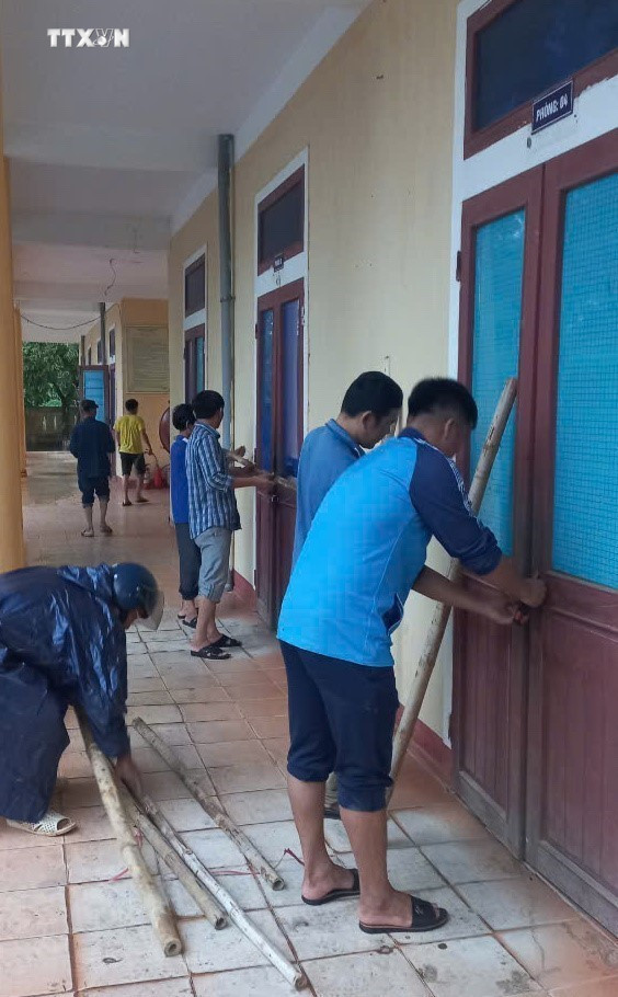 Các giáo viên chằng chống cửa lớp học để ứng phó bão số 4. Ảnh: TTXVN phát vna_potal_quang_tri_trien_khai_cac_giai_phap_ung_pho_voi__mua_lon_sat_lo_dat_7604586.jpg