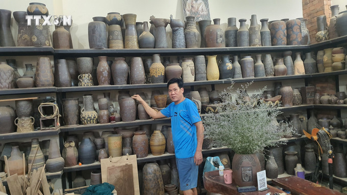 Anh Nguyễn Giang Anh, thị trấn Hương Canh, huyện Bình Xuyên giới thiệu về sản phẩm gốm Hương Canh của gia đình sản xuất. Ảnh: Nguyễn Trọng Lịch - TTXVN vna_potal_giu_gin_va_phat_huy_gia_tri_gom_huong_canh_vinh_phuc_7686137.jpg