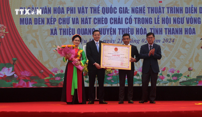 Ông Nông Quốc Thành, Phó Cục trưởng Cục Di sản Văn hoá trao Chứng nhận công nhận Danh mục di sản văn hóa phi vật thể quốc gia đối với nghệ thuật trình diễn dân gian "Múa đèn chạy chữ và hát chèo chải cổ" cho chính quyền và người dân làng Nhân Cao, xã Thiệu Quang và huyện Thiệu Hóa. Ảnh: Hoa Mai - TTXVN vna_potal_trinh_dien_dan_gian_mua_den_chay_chu_va_hat_cheo_chai_co_duoc_cong_nhan_di_san_van_hoa_phi_vat_the_quoc_gia_7235106.jpg