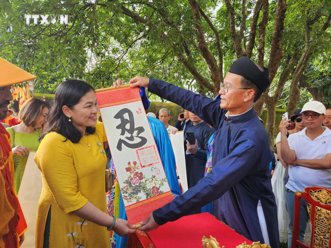 Tặng chữ đầu năm cho du khách tham quan Đại nội Huế. Ảnh: Mai Trang - TTXVN vna_potal_thua_thien_-_hue_to_chuc_le_ha_neu_va_khai_an_cung_chuc_tan_xuan_giap_thin_2024_7227667.jpeg