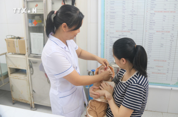 Cán bộ y tế phường Trần Lãm (thành phố Thái Bình) cho trẻ uống Vitamin A. Ảnh: Thu Hoài - TTXVN vna_potal_thai_binh_thuc_hien_chien_dich_bo_sung_vitamin_a_cho_tre_7406809.jpg