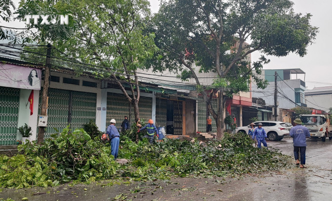 Công nhân Công ty Cổ phần Môi trường Đô thị tỉnh Lào Cai cắt dọn cây xanh bị gãy đổ để đảm bảo an toàn giao thông. Ảnh: Quốc Khánh - TTXVN vna_potal_dong_loc_mua_da_gay_ngap_ung_cay_xanh_gay_do_o_mot_so_tuyen_pho_tai_lao_cai_7361141.jpg