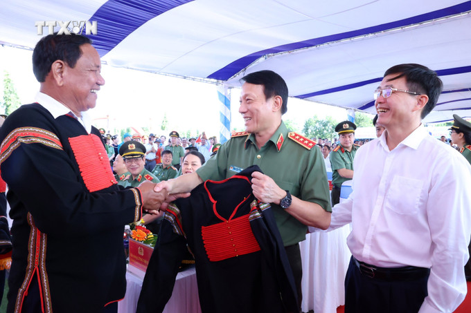 Già làng tặng Đại tướng Lương Tam Quang, Ủy viên Bộ Chính trị, Bộ trưởng Bộ Công an áo thổ cẩm của người Ê Đê tại Ngày hội. Ảnh: Hoài Thu – TTXVN vna_potal_dak_lak_ngay_hoi_dai_doan_ket_toan_dan_toc_va_tong_ket_de_an_ho_tro_xay_dung_1200_can_nha__7708149 (1).jpg