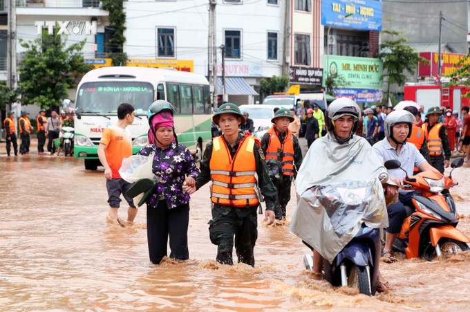 Bộ đội hỗ trợ người dân di chuyển qua khu vực bị ngập lụt tại thành phố Sơn La. Ảnh: Quang Quyết – TTXVN vna_potal_son_la_ung_pho_khan_cap_voi_nguy_co_mua_lon_tiep_tuc_tren_dien_rong_7505858.jpg