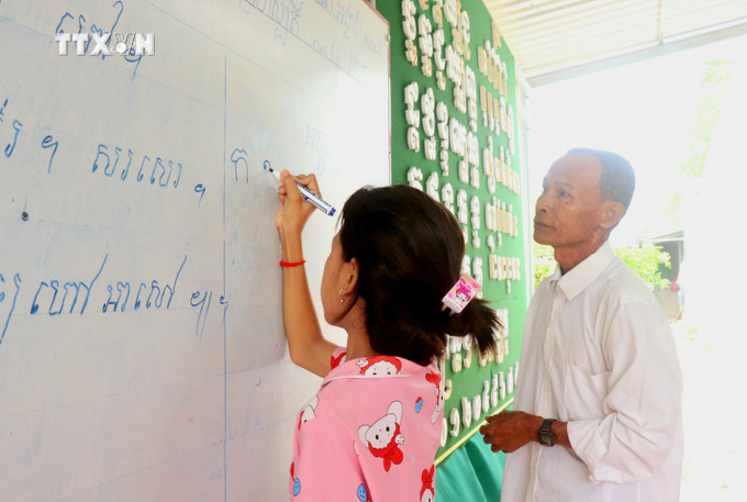 Ông Thạch Diễm, dạy đọc chữ Khmer cho các học sinh tại lớp dạy chữ Khmer ấp Thới Trường 1, xã Thới Xuân. Ảnh: Thu Hiền - TTXVN vna_potal_van_hoa_soi_duong_truyen_giu_chu_khmer_cho_the_he_sau_7484528.jpg