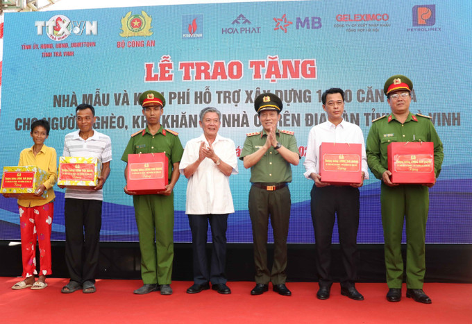 Thượng tướng Lương Tam Quang, Thứ trưởng Bộ Công an và Bí thư Tỉnh ủy Trà Vinh Ngô Chí Cường tặng quà cho địa phương và các hộ nhận nhà mới. Ảnh: Thanh Hòa-TTXVN vna_potal_bo_cong_an_ho_tro_xay_dung_1290_can_nha_cho_ho_ngheo_o_tra_vinh_7319361.jpg