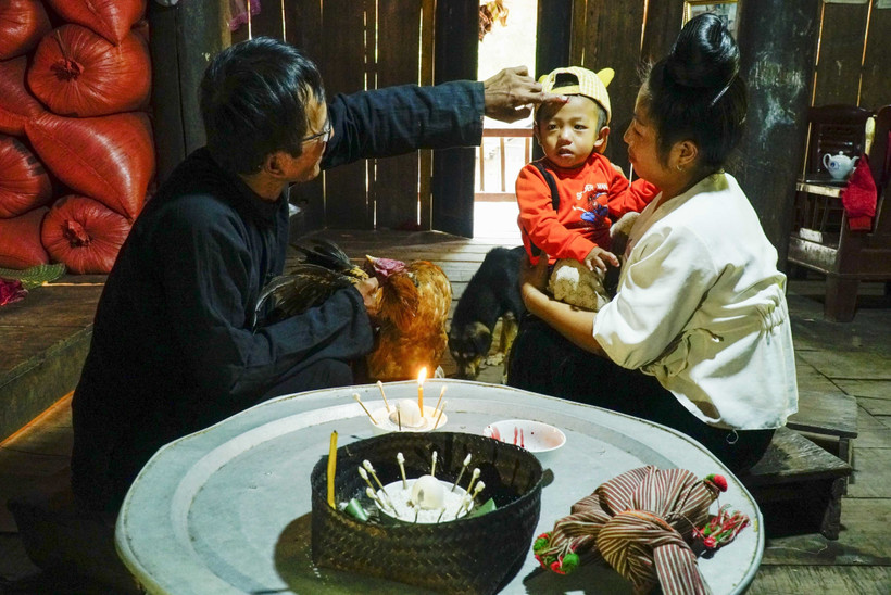 Nghi thức điểm chỉ, thầy cúng dùng tiết gà đánh dấu lên trán cho trẻ nhỏ để cầu xin thần linh phù hộ một năm mới không ốm đau, bệnh tật. Ảnh: Xuân Tư - TTXVN