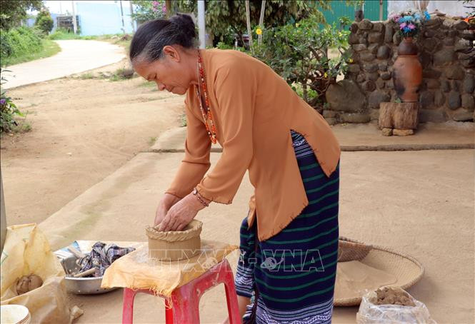 Để tạo hình tròn, nữ nghệ nhân này phải đi vòng quanh khối đất nặn, chứ không dùng bàn xoay như những nơi khác. Ảnh: Chu Quốc Hùng –TTXVN