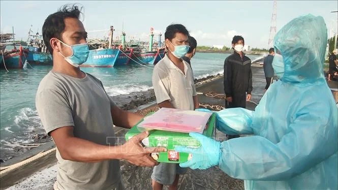 Đại diện đảo Sinh Tồn (bên phải) hỗ trợ nhu yếu phẩm và tặng cờ Tổ quốc cho ngư dân trước khi rời đảo tiếp tục chuyến đánh bắt hải sản. Ảnh: TTXVN phát